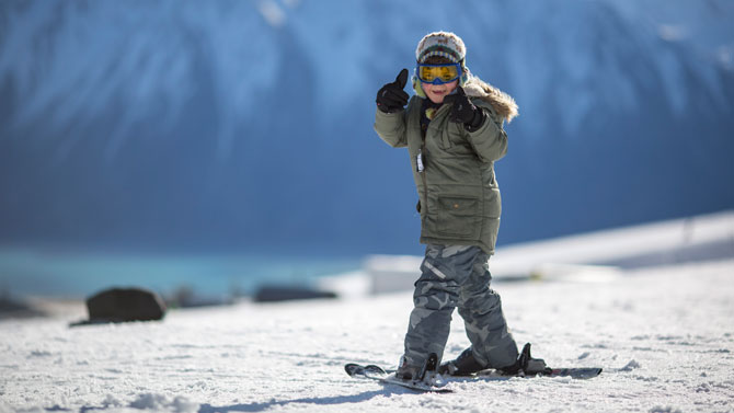 Young boy giving thumbs-up on snowboard